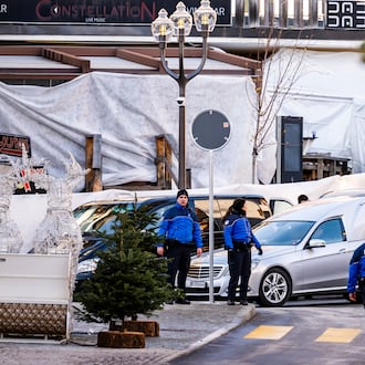 A hearse car drives as police officers inspect the area where a fire broke out at the Le Constellation bar and lounge during New Year's celebration, in Crans-Montana, Switzerland, Thursday, Jan. 1, 2026. (Jean-Christophe Bott/Keystone via AP)