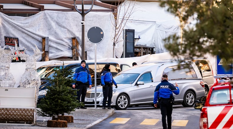 A hearse car drives as police officers inspect the area where a fire broke out at the Le Constellation bar and lounge during New Year's celebration, in Crans-Montana, Switzerland, Thursday, Jan. 1, 2026. (Jean-Christophe Bott/Keystone via AP)