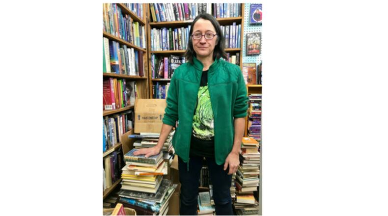 Kate Mooneyham, manager of Dark Star Books in Yellow Springs, stands next to a pile of books she plans to give away.