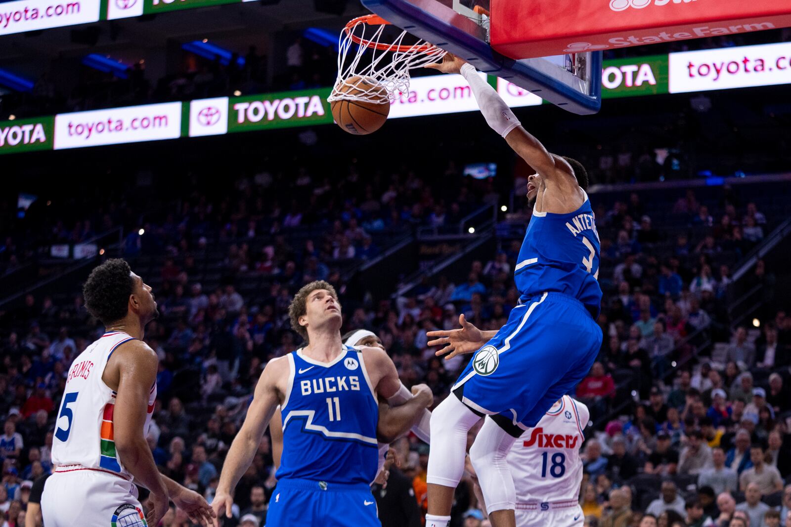 Milwaukee Bucks' Giannis Antetokounmpo, right, dunks the ball as Brook Lopez, center, and Philadelphia 76ers' Quentin Grimes, left, look on during the first half of an NBA basketball game, Thursday, April 3, 2025, in Philadelphia. (AP Photo/Chris Szagola)