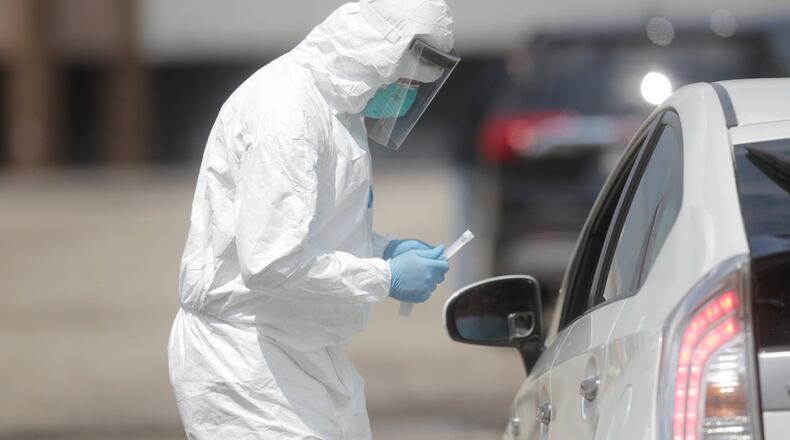 Nurse practitioner Emmanuel Dsouza administers a COVID-19 test in the parking lot of The Inspiration Church on Philadelphia Drive in Dayton last week. JIM NOELKER/STAFF
