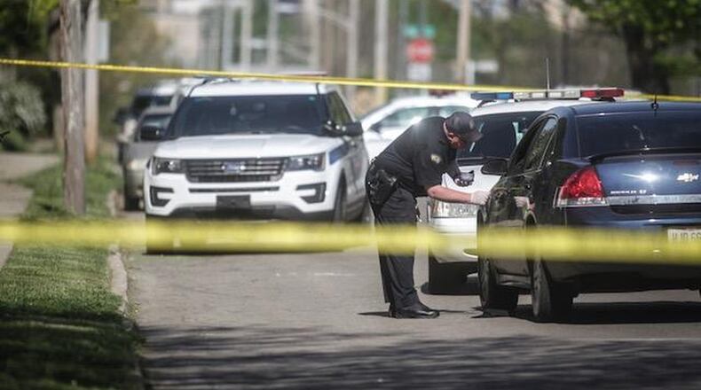 A Dayton police evidence technician examines a car found on West Second Street Tuesday, May 8, 2018. The victim found wounded in that car told police he was shot elsewhere and drove to a relative’s home on West Second Street. (Jim Noelker/Staff)