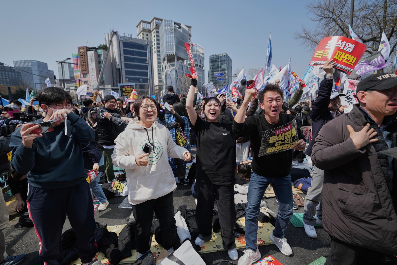 People react after hearing the news that President Yoon Suk Yeol was removed from office, in Seoul, South Korea, Friday, April 4, 2025. (AP Photo/Lee Jin-man)