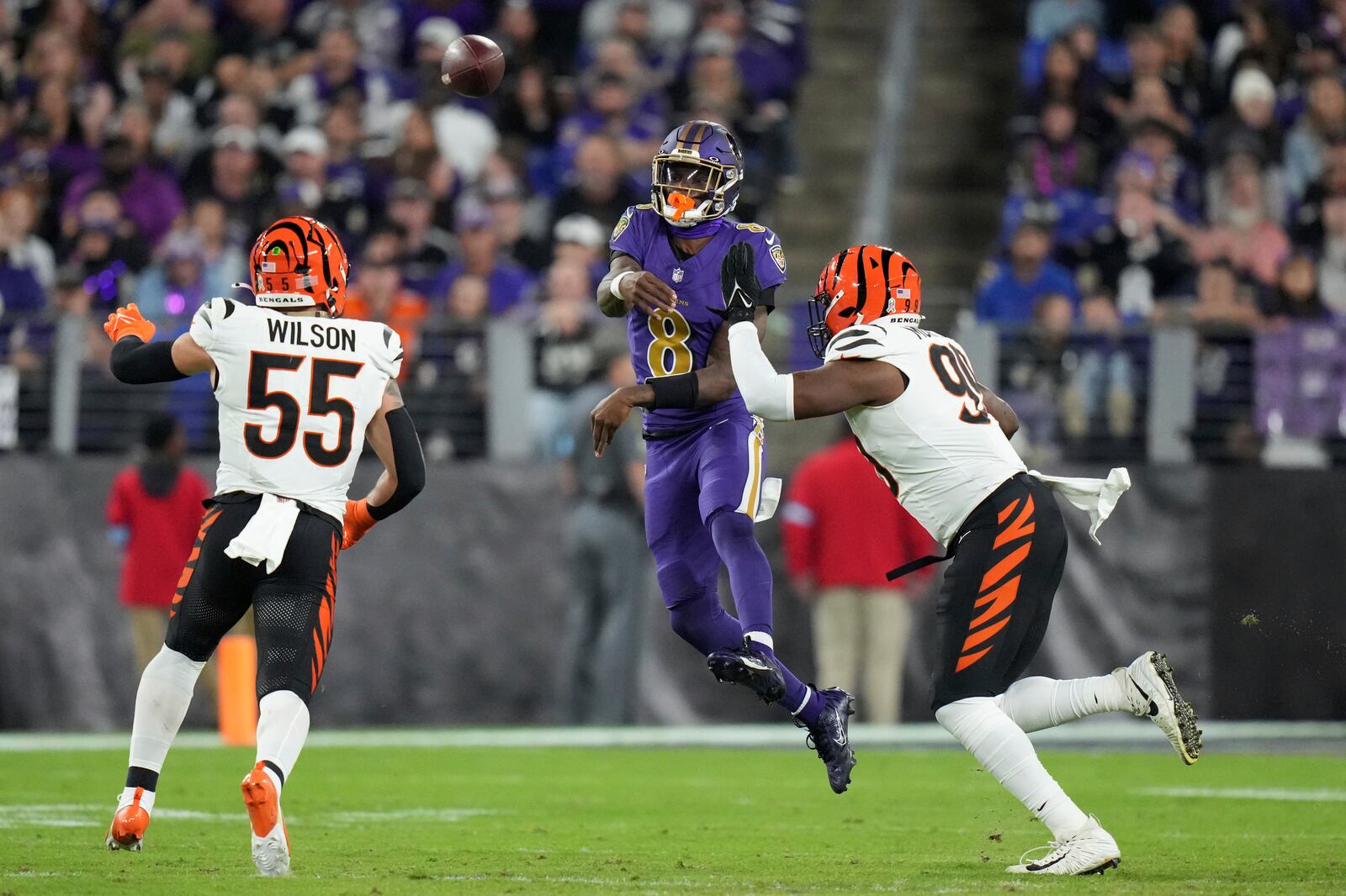 Baltimore Ravens quarterback Lamar Jackson (8) throws under pressure from Cincinnati Bengals defensive end Myles Murphy (99) and linebacker Logan Wilson (55) during the second half of an NFL football game, Thursday, Nov. 7, 2024, in Baltimore. (AP Photo/Stephanie Scarbrough)
