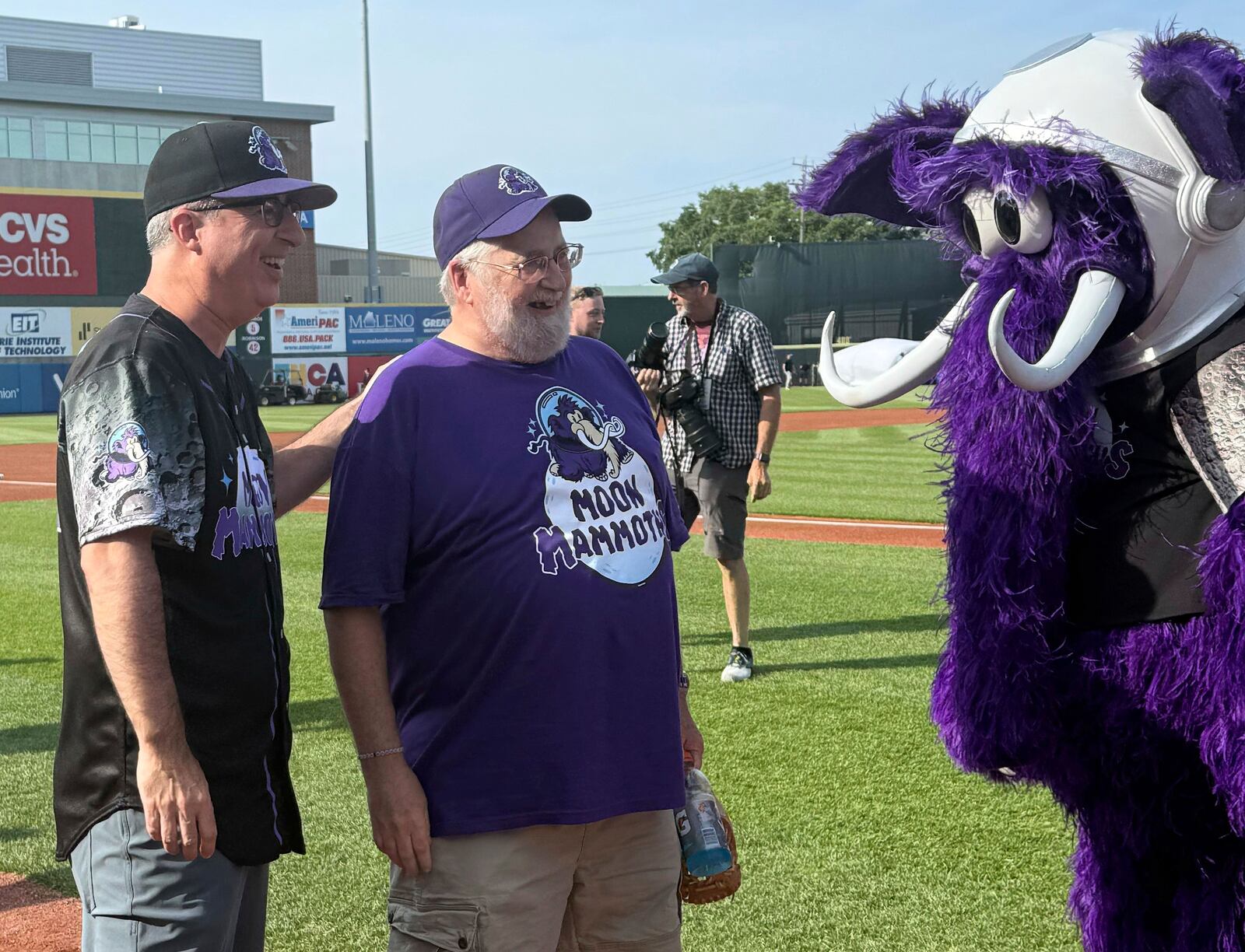 John Oliver, left, and George Moon stand with Fuzz E. Mammoth, the Moon Mammoth mascot, before a game between the Chesapeake Oyster Catches and Erie Moon Mammoths at UMPC Park in Erie, Pa., on Saturday, July 19, 2025. (AP Photo/Joe Reedy)