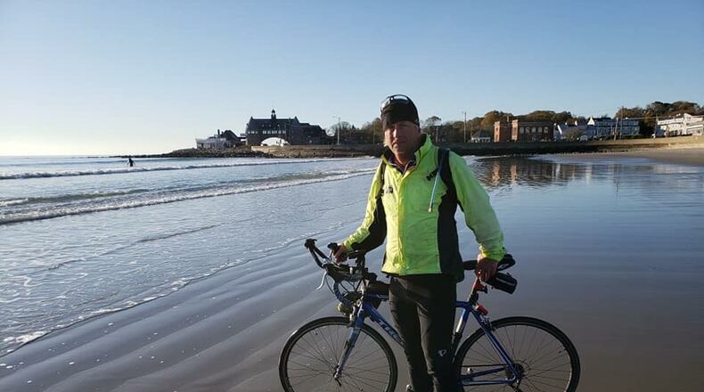 Earl McDaniel ceremoniously dips his bike tire in the Narragansett Bay marking the end of his cross-country bike trip. CONTRIBUTED
