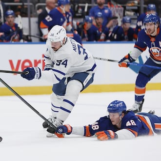 New York Islanders' Matthew Schaefer (48) reaches for the puck against Toronto Maple Leafs center Auston Matthews (34) during the first period of an NHL hockey game, Saturday, Jan. 3, 2026, in New York. (AP Photo/Heather Khalifa)