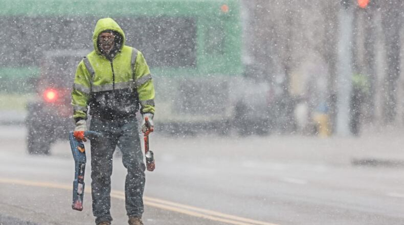 Josh Mosley, from Hamilton, tries to locate a fiber optic line under Third Street in Dayton during a snowsquall Monday December 18, 2023. JIM NOELKER/STAFF