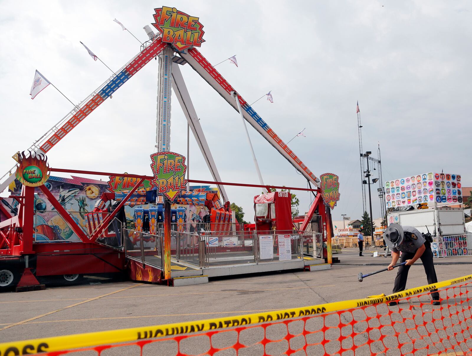 A trooper with the Ohio Highway Patrol removes a ground spike in front of the Fire Ball ride July 27, 2017, at the Ohio State Fair in Columbus, Ohio, the day after it broke apart, killing an 18-year-old and injuring seven others.