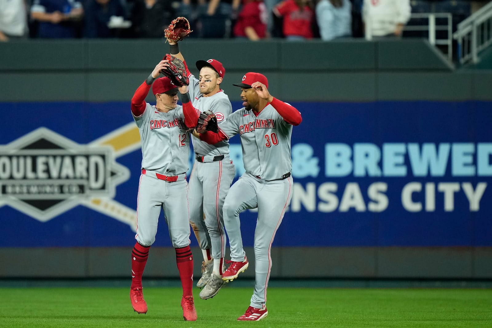 Cincinnati Reds outfielders Austin Hays, left, TJ Friedl, center and Will Benson celebrate after their baseball game against the Kansas City Royals, Tuesday, May 27, 2025, in Kansas City, Mo. (AP Photo/Charlie Riedel)