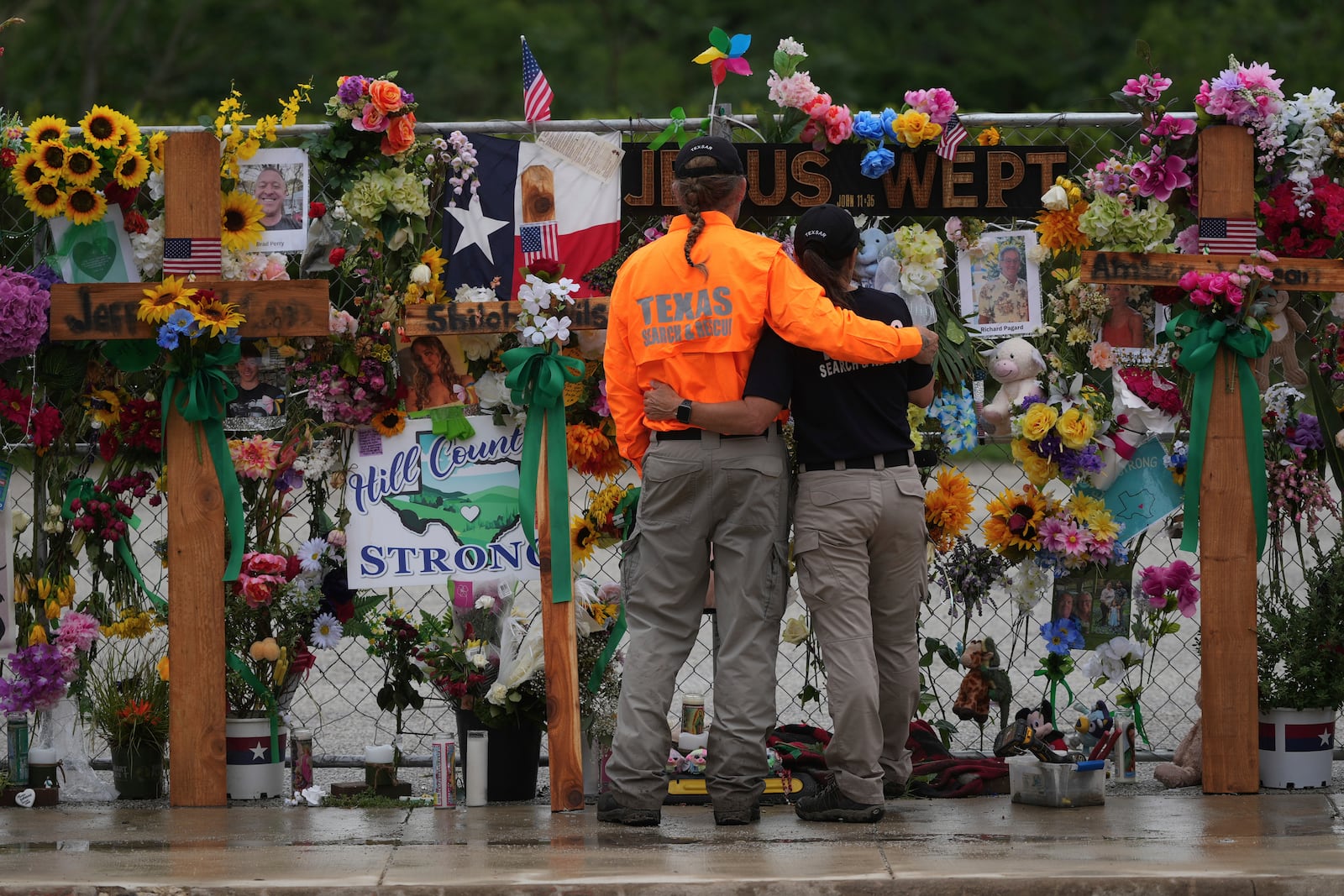 FILE - Members of a search and rescue team embrace as they visit a memorial wall for flood victims, Sunday, July 13, 2025, in Kerrville, Texas. (AP Photo/Eric Gay, File)