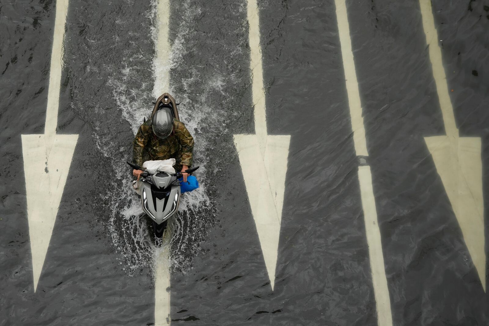 A rider drives his motorcycle along a flooded road following tropical storm Wipha fueled monsoon rains in Manila, Philippines on Tuesday, July 22, 2025. (AP Photo/Aaron Favila)