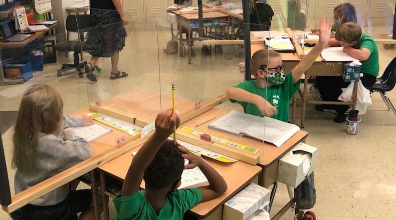 Second-graders raise their hands to answer a question about synonyms in Carol Keating's classroom at St. Brigid's Catholic School in Xenia on Friday, Sept. 25, 2020.