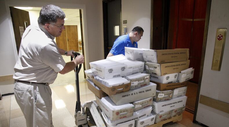 Tim Davis (left), director of mailing services for the Montgomery County Board of Elections, and Kim Wong, an IT specialist, transport a load of absentee ballots to be mailed out in this 2012 file photo. FILE
