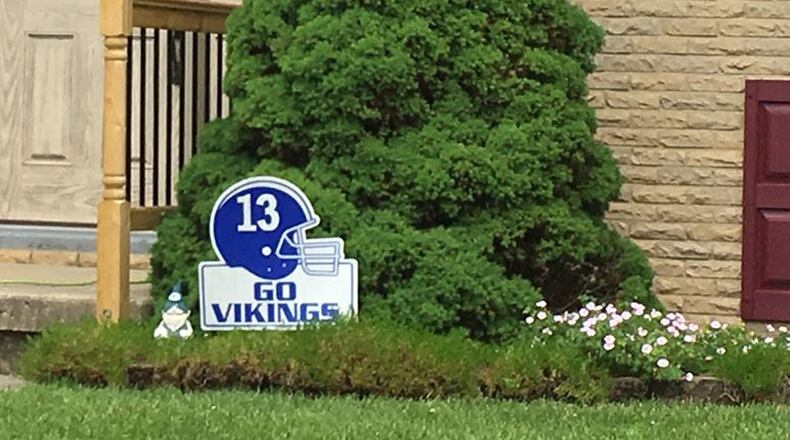 A sign outside Darren Hamblin’s home in Miamisburg shows his late son Cody’s No. 13 on a blue helmet. Hamblin’s lawsuit against helmet manufacturer Riddell is continuing in Montgomery County Common Pleas Court. STAFF