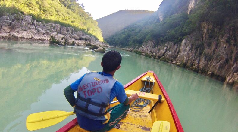 A river guide paddles up the milky green Tampaon River in a wooden canoe. (Mark Johanson/Chicago Tribune/TNS)