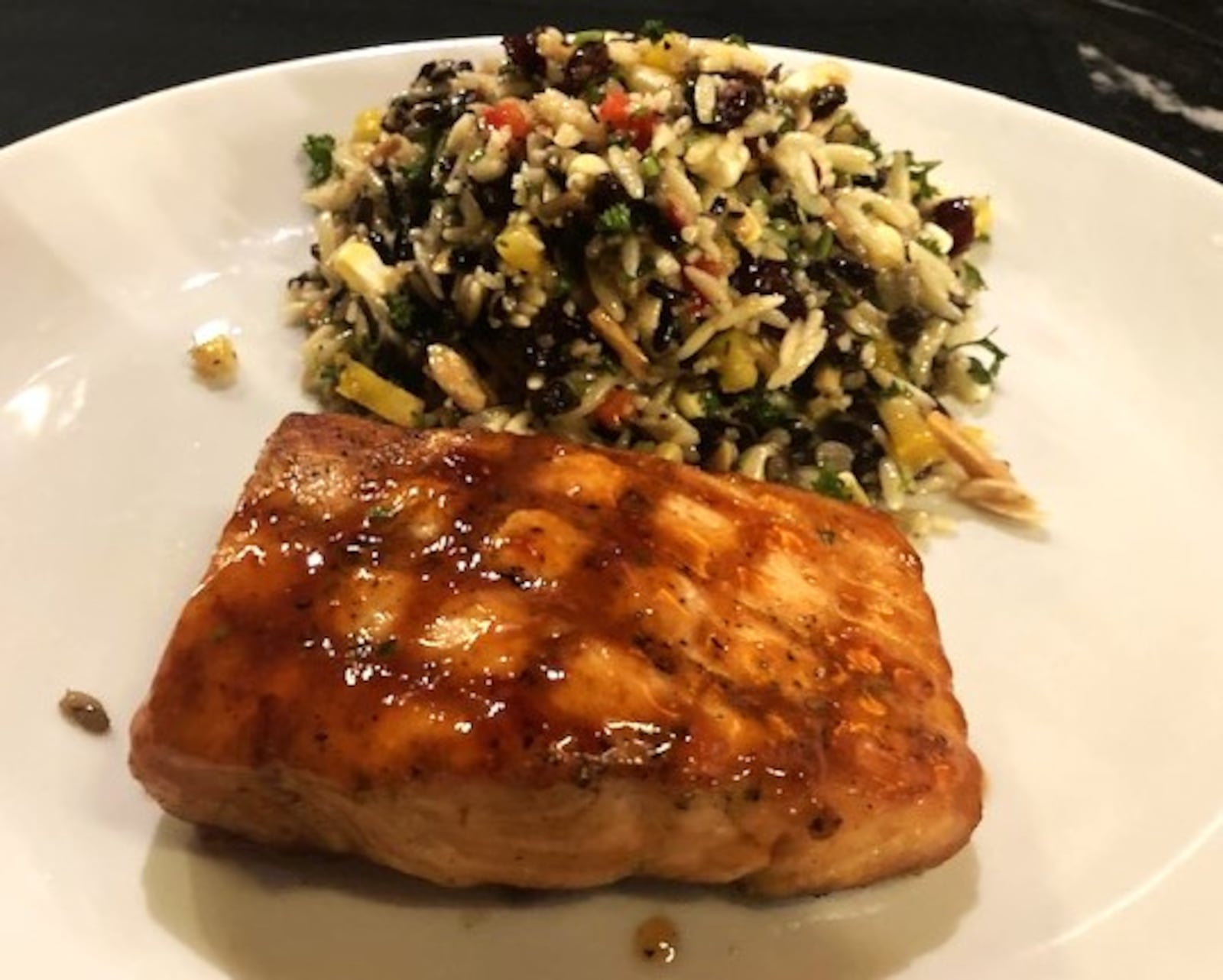 The Thai barbecue-glazed salmon with orzo and wild rice at J. Alexander's in Dayton has flavorful orzo with almond slivers, red winter wheat, cranberries, corn, currants, and other ingredients. RAY MARCANO/CONTRIBUTED