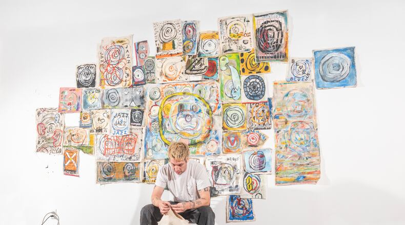 Dayton-based artist Kyle Thiele, in front of his ever-growing collection of raw canvas paintings, mounts a solo exhibition at The Blue House Gallery. JESSE LY/CONTRIBUTED