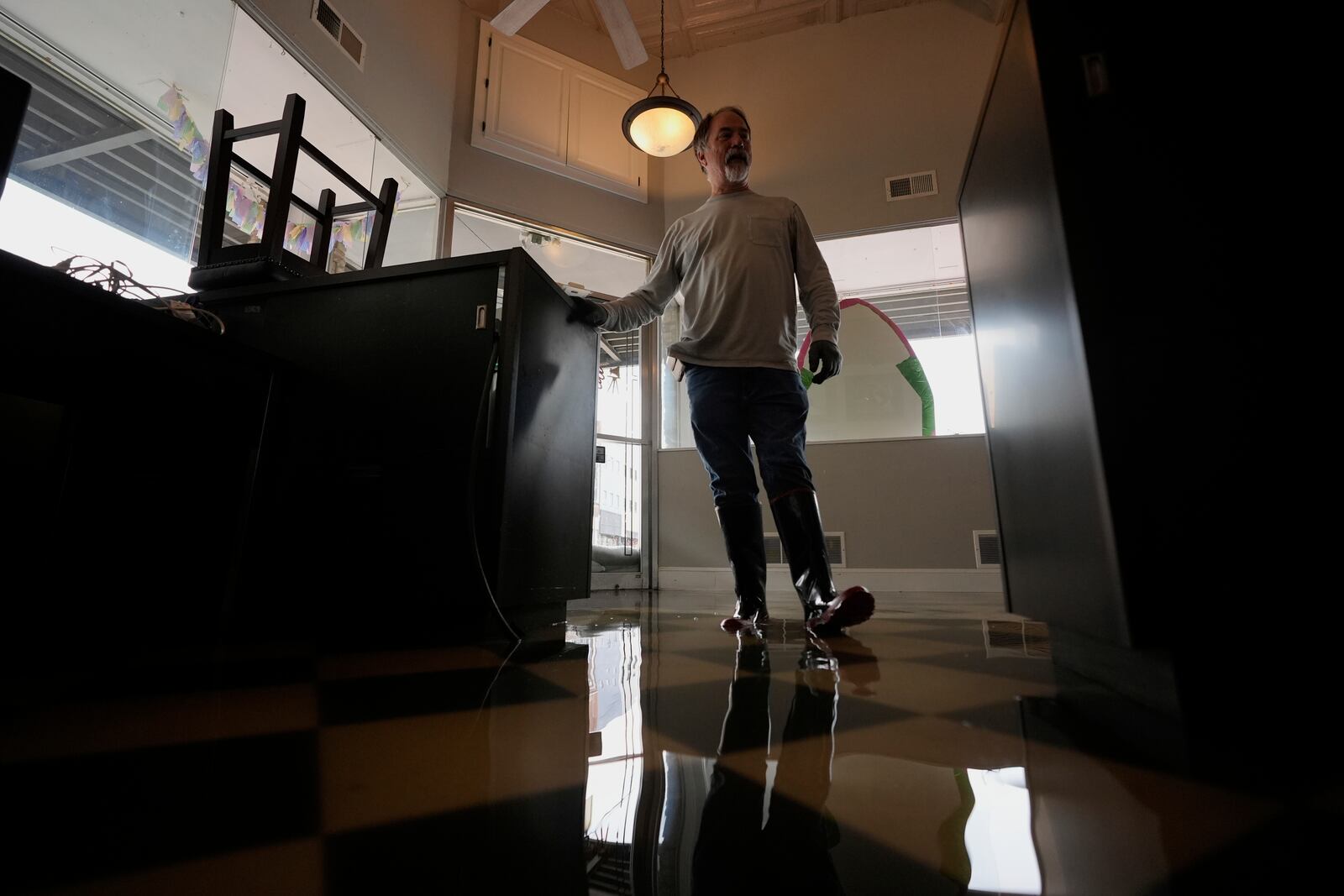 Tony Kirves prepares for flooding inside this photography studio in Hopkinsville, Ky., Friday, April 4, 2025. (AP Photo/George Walker IV)
