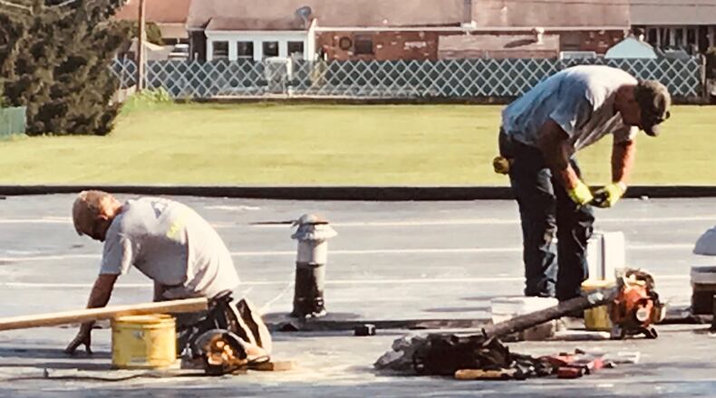 Workers from American Roofing and Metal Company work to replace portions of the roof at Cookson Elementary School in Troy.