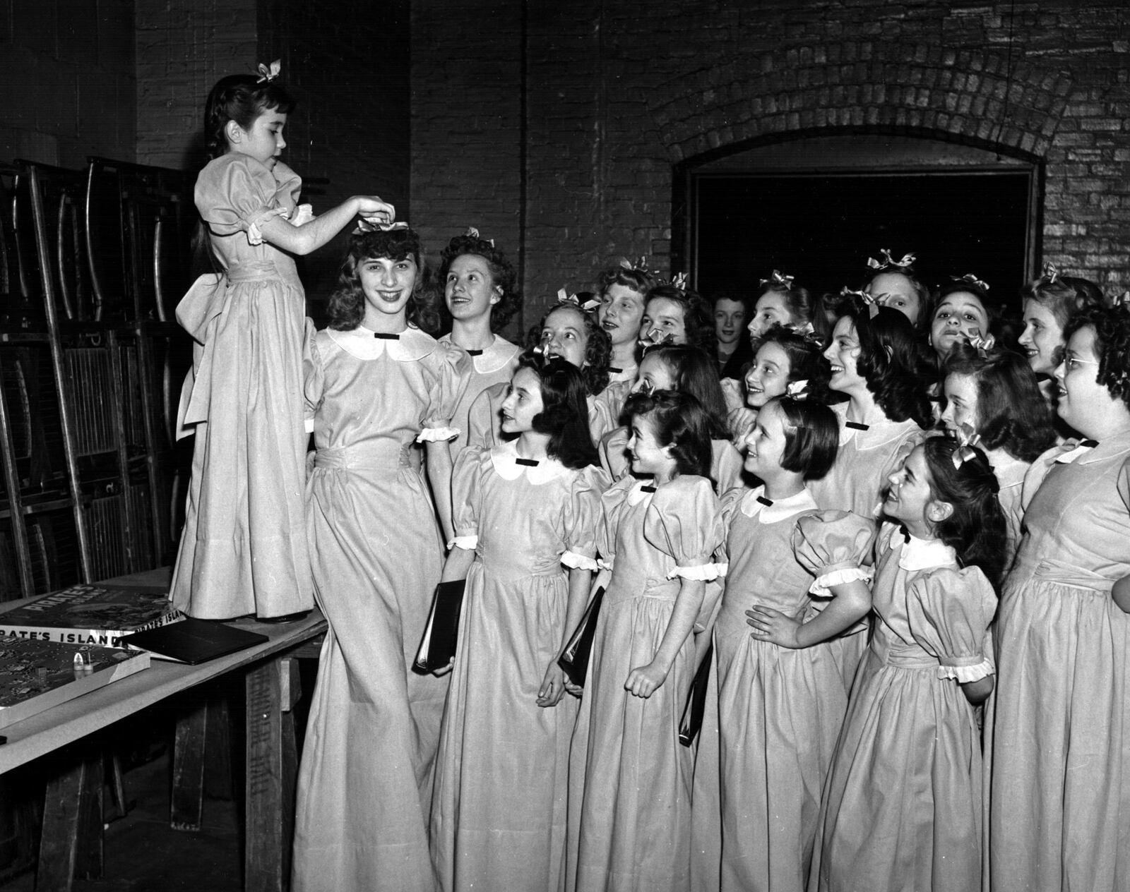 Linda Crumb adjusts the bow of another Inland Children’s Chorus member in a 1942 publicity photograph. Photo: InlandChorus.com