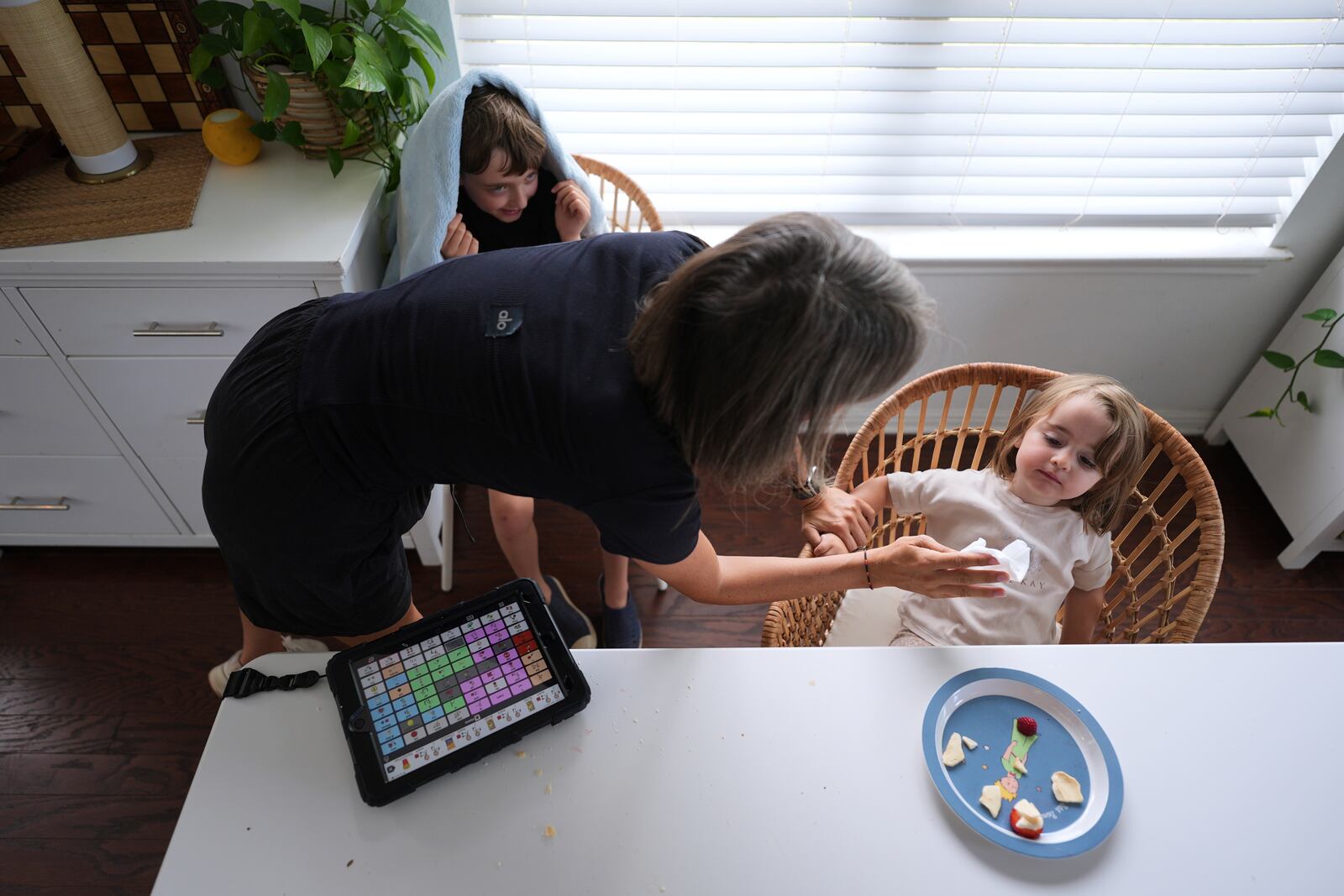 Eileen Lamb, who was diagnosed with autism as an adult, left, works with her son Charlie Lamb, top, who also has autism, and daughter Billie, at heir home, Monday, May 12, 2025, in Austin, Texas. (AP Photo/Eric Gay)