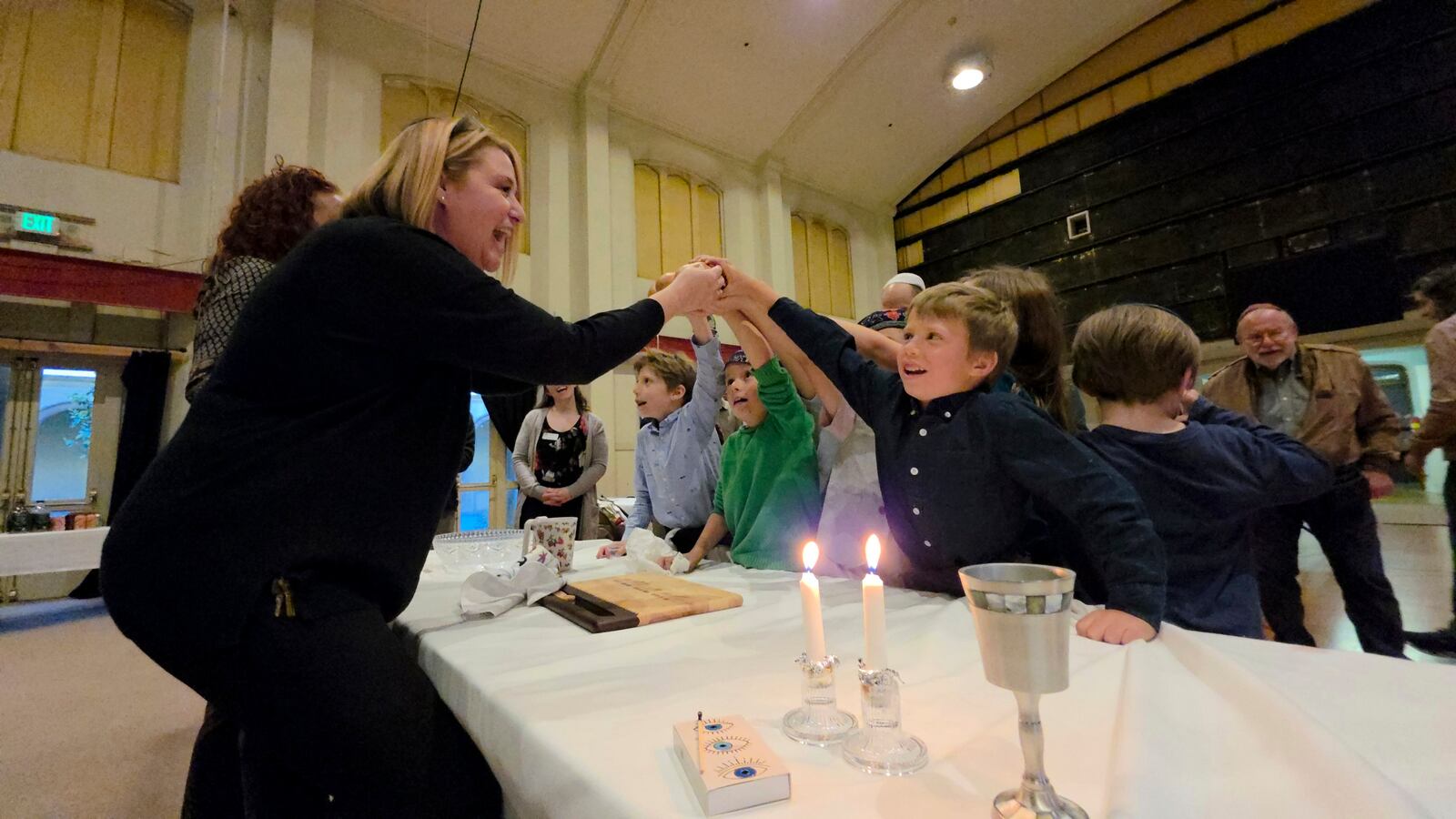 Cantor Ruth Berman Harris, left, who leads the congregation in lieu of a full-time rabbi, celebrates Seder by eating matzah with congregants of the 104-year-old Pasadena Jewish Temple and Center which burned down in the Jan. 2025 Eaton fire, gathered for a Passover at the First United Methodist Church in Pasadena, Calif. on Friday, April 4, 2025. (AP Photo/Damian Dovarganes)