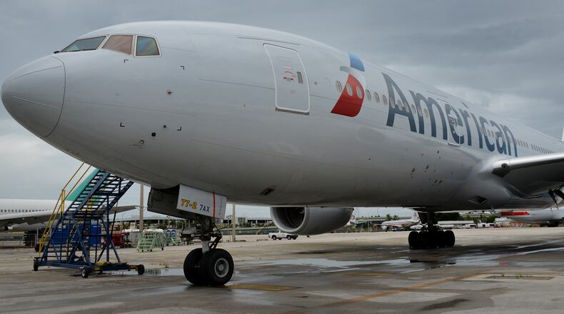 An American Airlines jet parked at a terminal of Miami International Airport in 2014. The world’s largest airline plans to stop on-board announcements of connecting gate information as flights prepare to land. Bloomberg photo by Mark Elias.