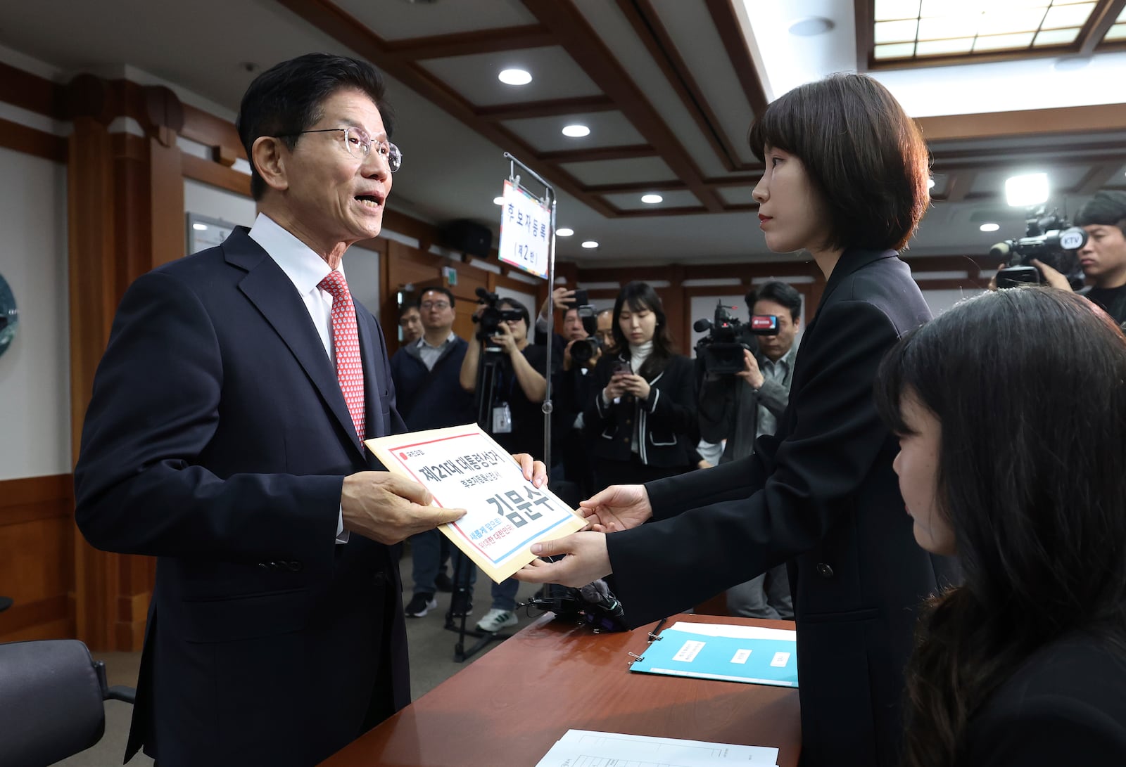 South Korea's People Power Party's presidential election candidate Kim Moon Soo, left, submits documents to register as a candidate to run in the June 3 presidential election, at the National Election Commission, Gwacheon, South Korea, Sunday, May 11, 2025. The letter read "The 21st Presidential election candidate registration application, Kim Moon Soo." (Yonhap via AP)