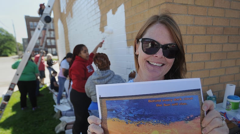 Brittini Long, senior program coordinator for the Montgomery County Alcohol, Drug Addiction and Mental Health Services board, which provides support to the Montgomery County Prevention Coalition, holds a print Friday, May 31, 2024 of what the mural will look like on the side of Tuffy Brooks Sporting Goods, located at 101 S. Keowee St. in Dayton. MARSHALL GORBY\STAFF