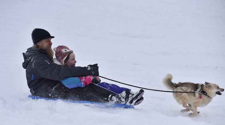 Jason Bender and Breanna Bender, 8, sled IN the snow with their dog, Lucy, Tuesday, February 9, 2021 at Harbin Park in Fairfield. NICK GRAHAM  / STAFF