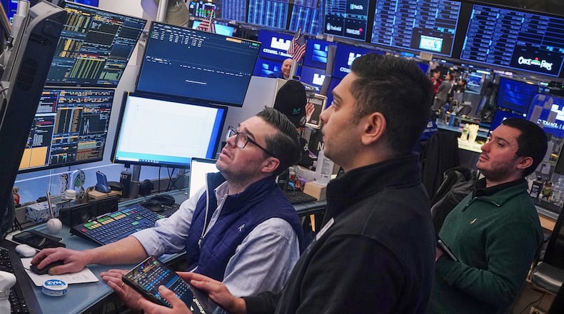 Traders Joseph Lawler, left, and Niall Pawa, center, and Drew Cohen work on the floor of the New York Stock Exchange, Thursday, Feb. 19, 2026. (AP Photo/Richard Drew)