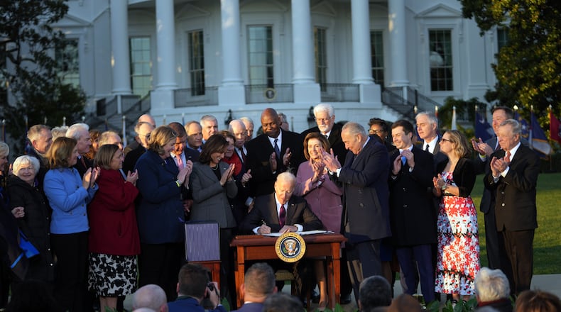 As Dayton Mayor Nan Whaley and members of Congress and other officials look on, President Joe Biden signs the $1 trillion infrastructure bill into law at the White House on Monday, Nov. 15, 2021. (Doug Mills/The New York Times)