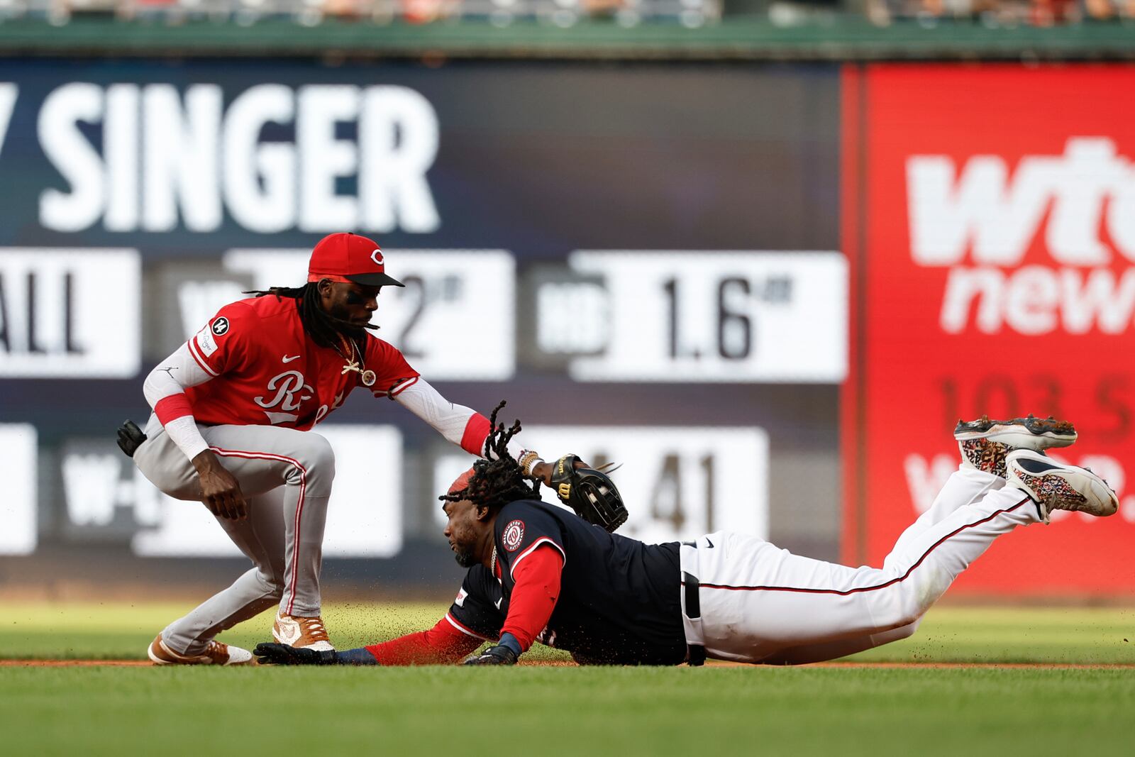 Washington Nationals' Josh Bell, right, avoids a tag by Cincinnati Reds shortstop Elly De La Cruz, left, and slides into second base on a double hit off pitcher Brady Singer during the first inning of a baseball game in Washington, Monday, July 21, 2025. (AP Photo/Terrance Williams)