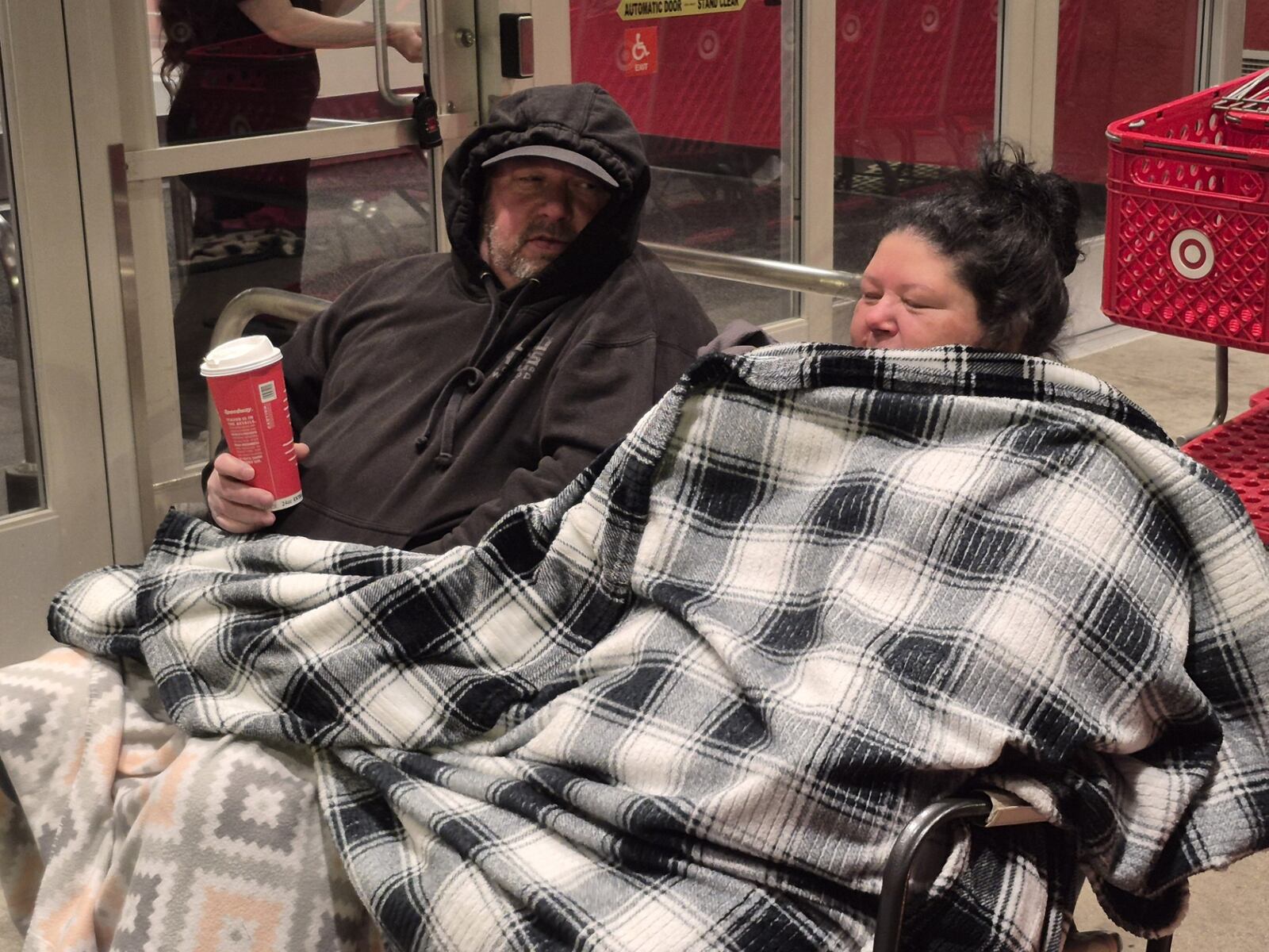 John and Virginia Nesbit huddle beneath a blanket while waiting for the Beavercreek Target store to open on Black Friday. Some retailers used giveaways to drive traffic to their stores for the Thanksgiving shopping weekend. MICHAEL KURTZ / STAFF