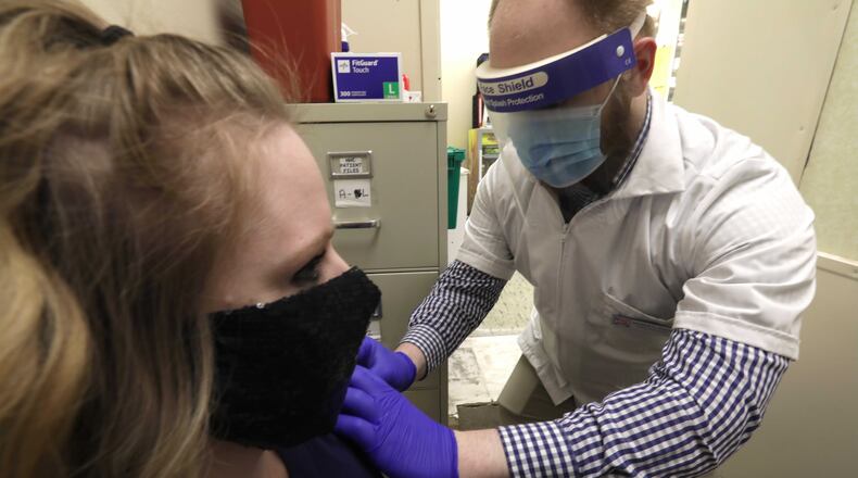 Andrew Hoffman, a pharmacist at Discount Drug Mart in Enon, gives Jennifer Boswell a flu shot at the pharmacy Thursday. BILL LACKEY/STAFF
