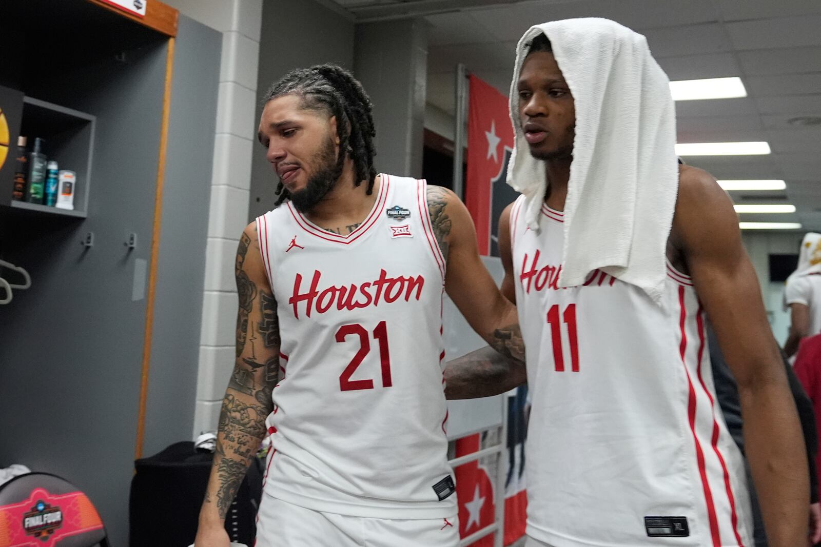 Houston's Emanuel Sharp (21) and Joseph Tugler (11) hug in the locker room after Florida beat Houston in the national championship at the Final Four of the NCAA college basketball tournament, Monday, April 7, 2025, in San Antonio. (AP Photo/Stephanie Scarbrough)