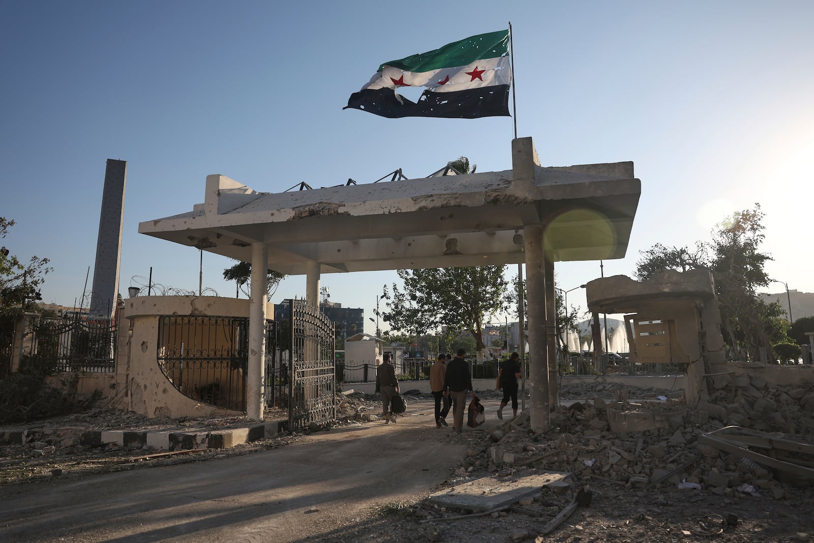 Security members carry belongings as they leave the damaged Syrian Defense Ministry building allegedly hit by several Israeli airstrikes, in Damascus, Syria, Wednesday, July 16, 2025. (AP Photo/Ghaith Alsayed)