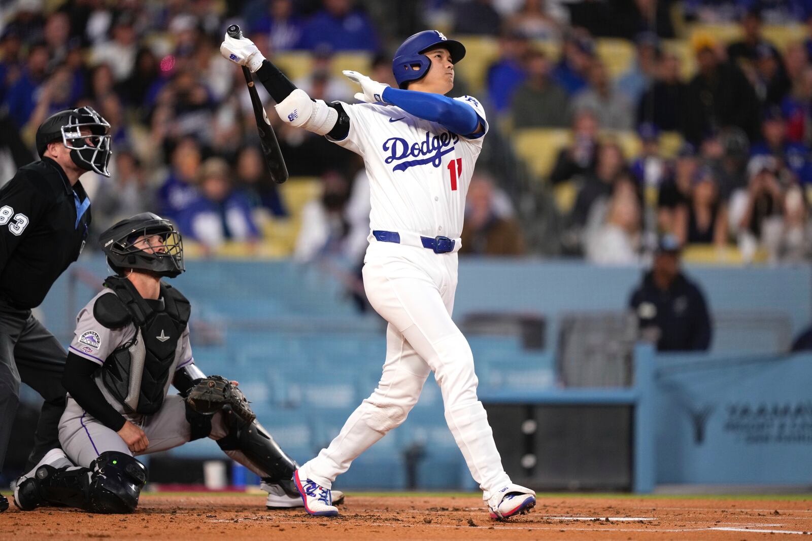 Los Angeles Dodgers' Shohei Ohtani, right, hits a solo home run as Colorado Rockies catcher Braxton Fulford watches along with home plate umpire Doug Eddings during the first inning of a baseball game against the Colorado Rockies Wednesday, April 16, 2025, in Los Angeles. (AP Photo/Mark J. Terrill)