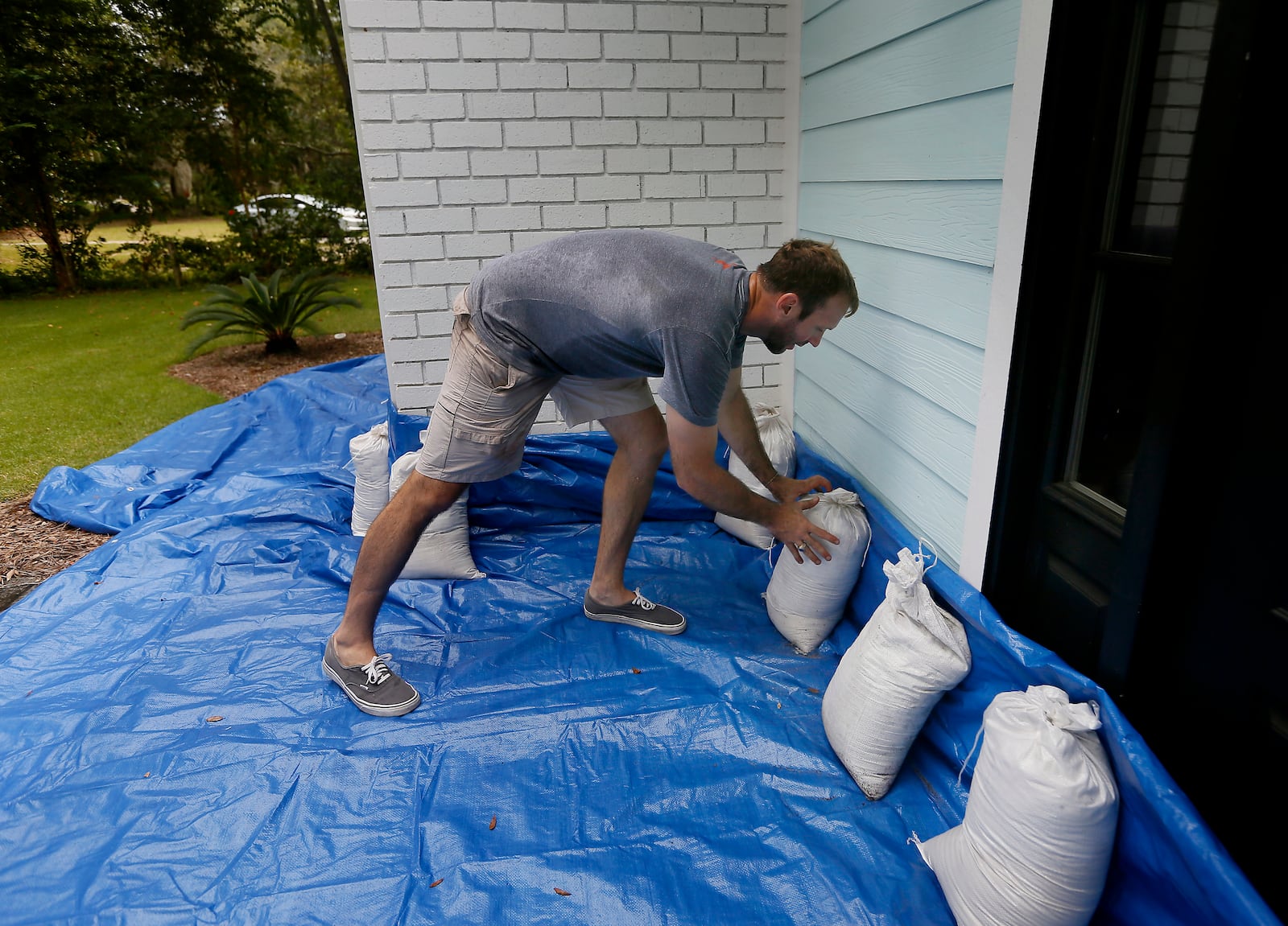 FILE - Stewart Thomason places sandbags that he used for previous hurricanes and tarp to prevent the flooding from rain at his home on the Isle of Palms, S.C. ahead of Hurricane Florence, on Wednesday, Sept. 12, 2018. (Grace Beahm Alford/The Post And Courier via AP,File)