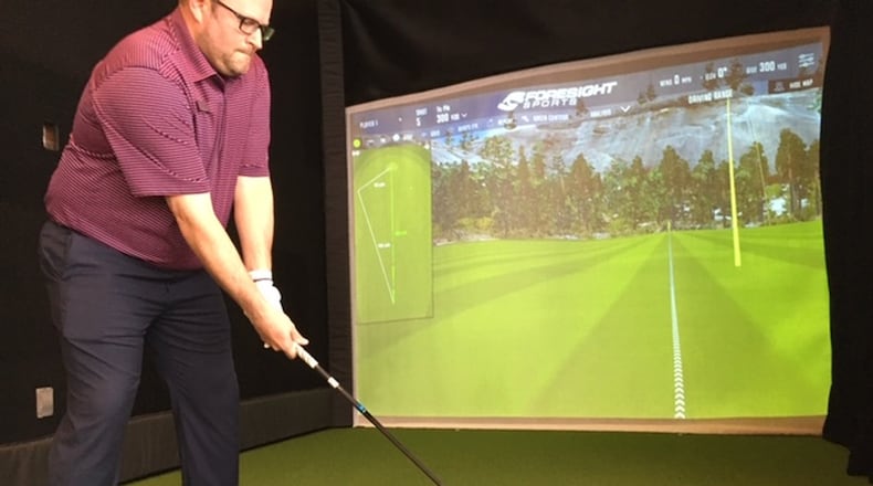 Matt Cole, golf pro at Heatherwoode Golf Club in Springboro, prepares to swing at a golf simulator in his course pro shop. Cole said the simulator has been quite popular and is helpful with training and fitting golfers with the right clubs. THOMAS GNAU/STAFF