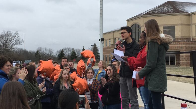 Riley Weisman, (left), a junior at Springboro High School, speaks at the walkout at Springboro High School, as schoolmates Suhavi Salmon and Ella Bowman (right) join him in front of about 500 students in the school’s parking lot Wednesday. LAWRENCE BUDD / STAFF