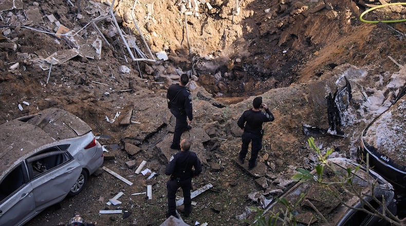 Israeli security forces and rescue teams inspect the site of an Iranian missile strike in Tel Aviv, Israel, Tuesday, March 24, 2026. (AP Photo/Oded Balilty)