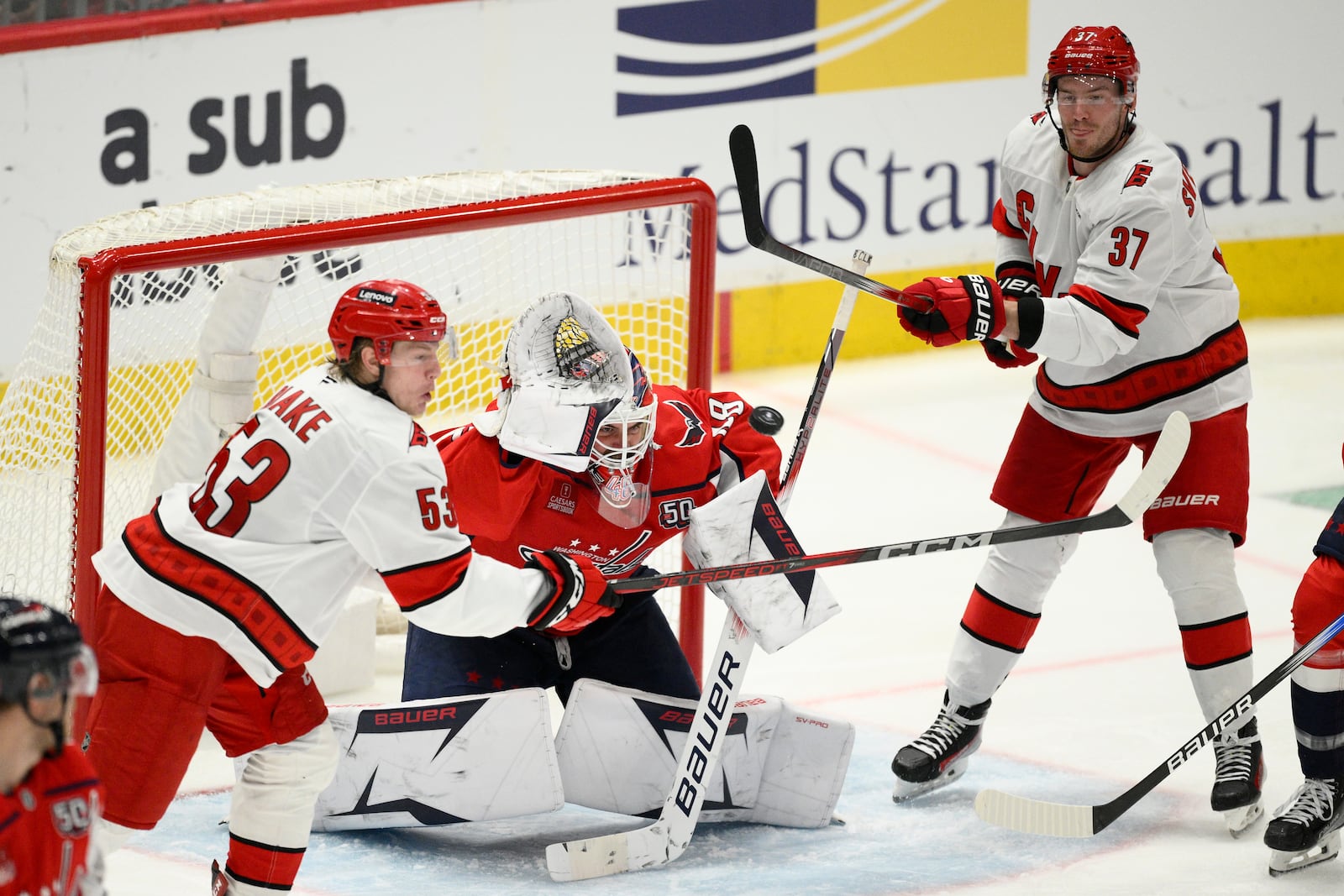 Washington Capitals goaltender Logan Thompson (48) looks for the puck against Carolina Hurricanes right wing Andrei Svechnikov (37) and right wing Jackson Blake (53) in the third period of Game 1 of a second-round NHL hockey playoff series Tuesday, May 6, 2025, in Washington. (AP Photo/Nick Wass)