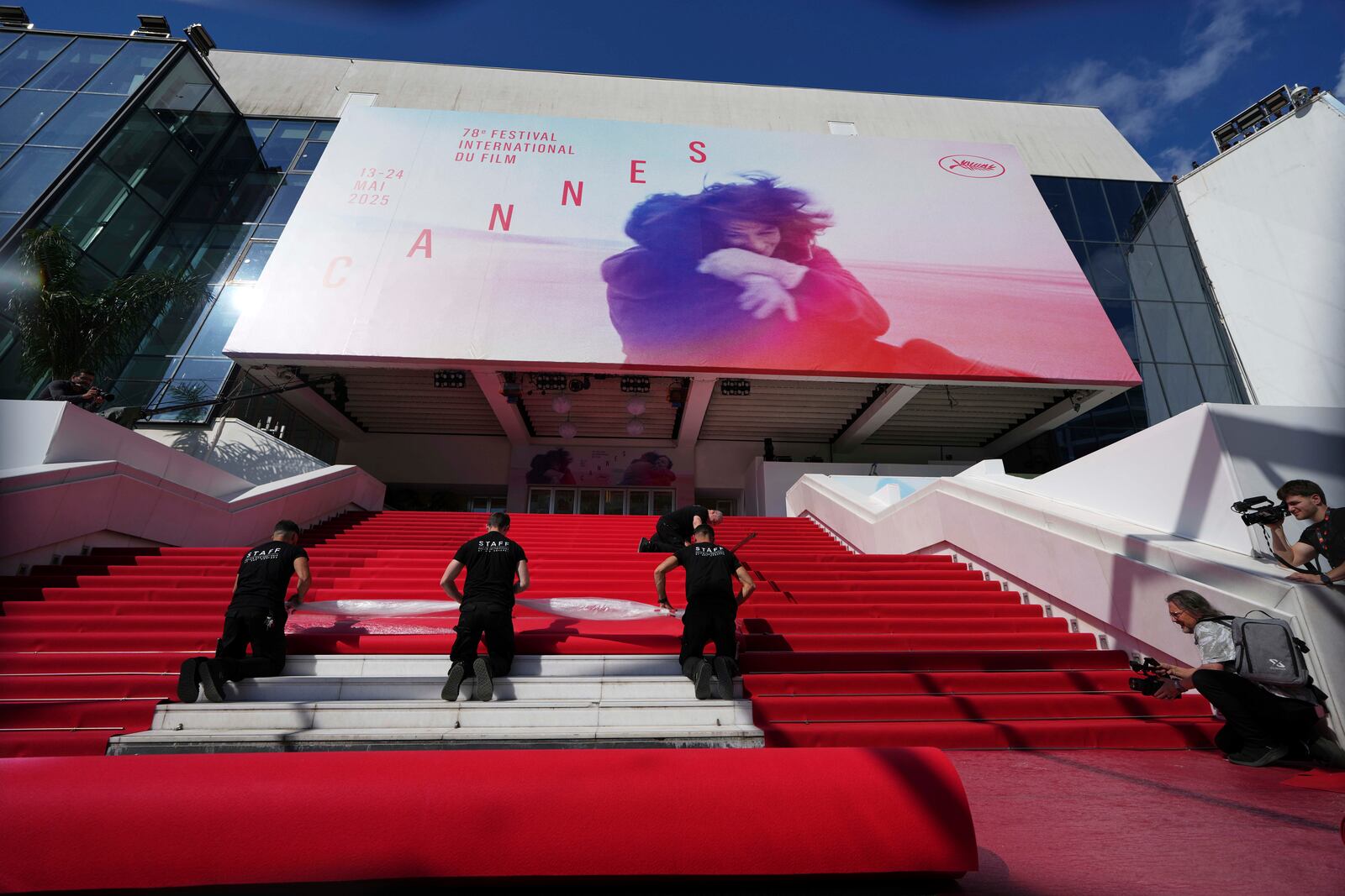 Crew members install the red carpet at the Palais des Festivals ahead of the opening ceremony of the 78th international film festival, Cannes, southern France, Tuesday, May 13, 2025. (AP Photo/Natacha Pisarenko)