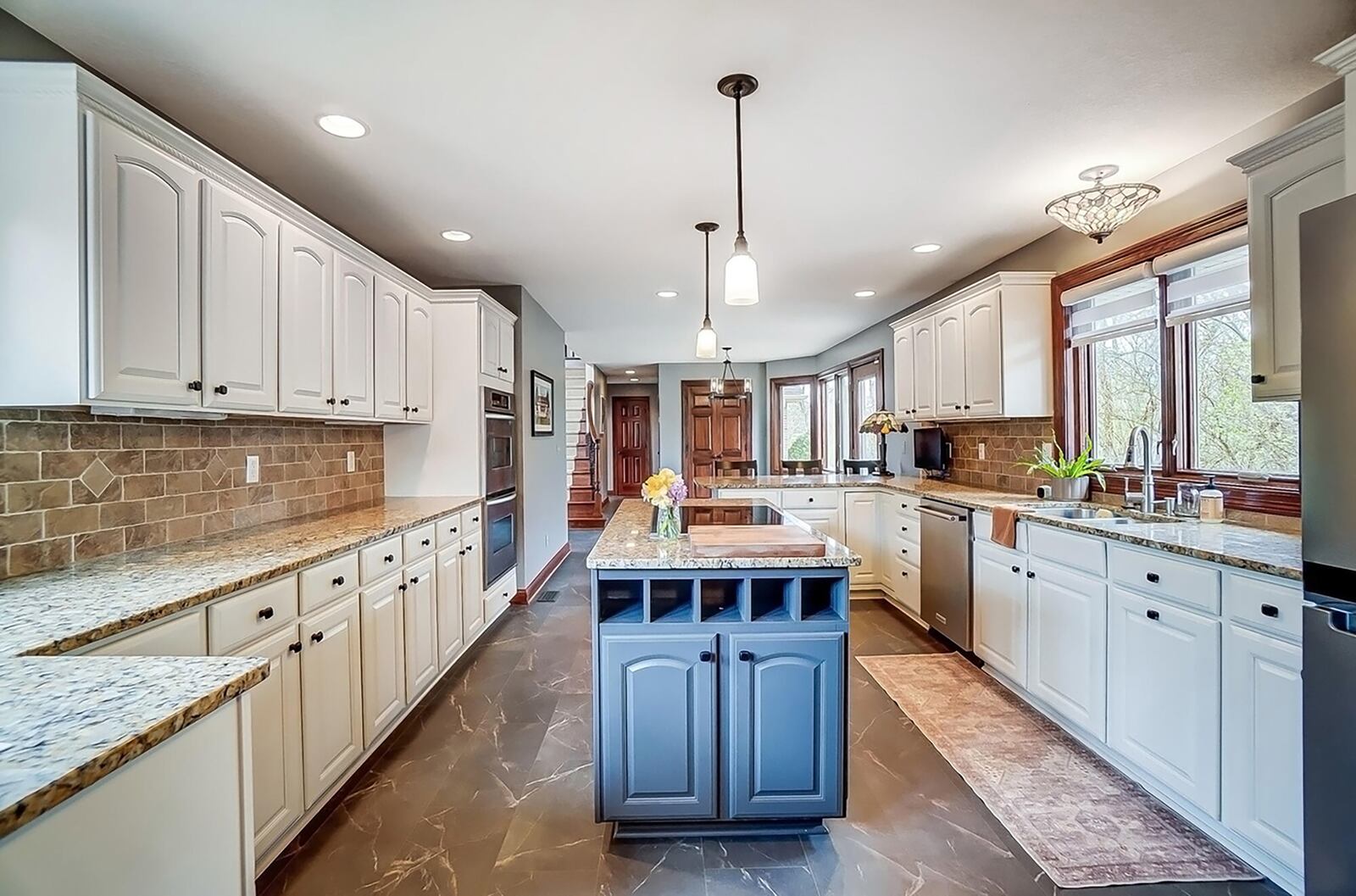 The kitchen has an eat in breakfast area and a bar with room for seating. It has granite countertops and tile backsplash and a separate island with electric cooktop.