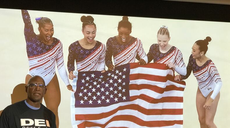 Michael Carter, the Chief Diversity Officer at Sinclair Community College and once the head basketball coach at Springfield South and Trotwood Madison high schools, stands in front of a photo of the gold-medal winning U.S. women’s gymnastics team at the 2024 Olympic Games in Paris. The quintet – (left to right) Jodan Sparks, Hezly Rivera, Simone Biles, Jade Carey and Suni Lee – are the most racially-diverse team in U.S. Olympic history and were one of the examples Carter used in his presentation last week about the way sports has been at the forefront of the positive results that come from DEI (Diversity, Equity and Inclusion) Tom Archdeacon/CONTRIBUTED