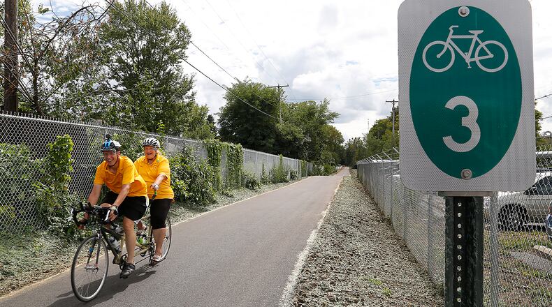 Brent and Meg Anderson ride their tandem bicycle along the new stretch of the Little Miami Scenic Trail following the ribbon cutting ceremony for the trail Friday. Bill Lackey/Staff