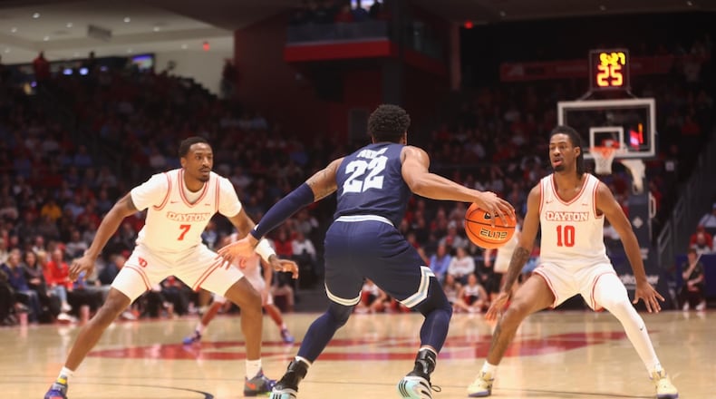 Dayton's Keonte Jones, left, and Bryce Heard, right, trap Rhode Island's RJ Johnson in the first half on Tuesday, Jan. 27, 2026, at UD Arena. David Jablonski/Staff