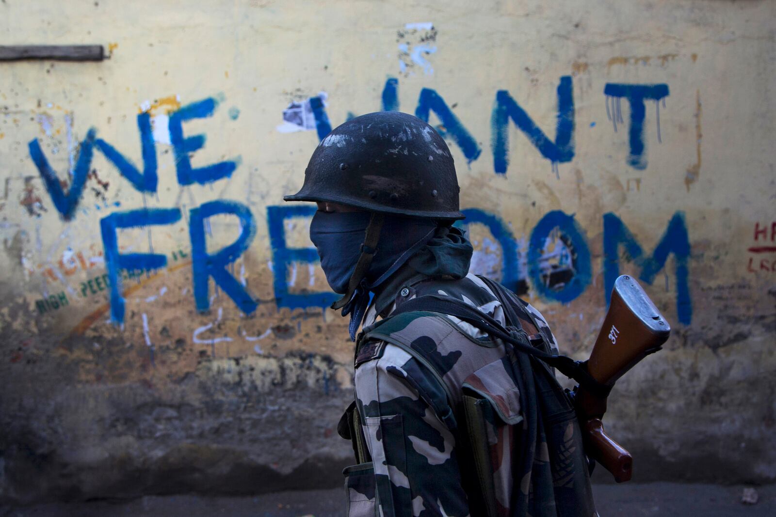 FILE - An Indian paramilitary soldier walks past graffiti on a wall in Srinagar, Indian-controlled Kashmir, Aug. 29, 2016. (AP Photo/Dar Yasin, File)